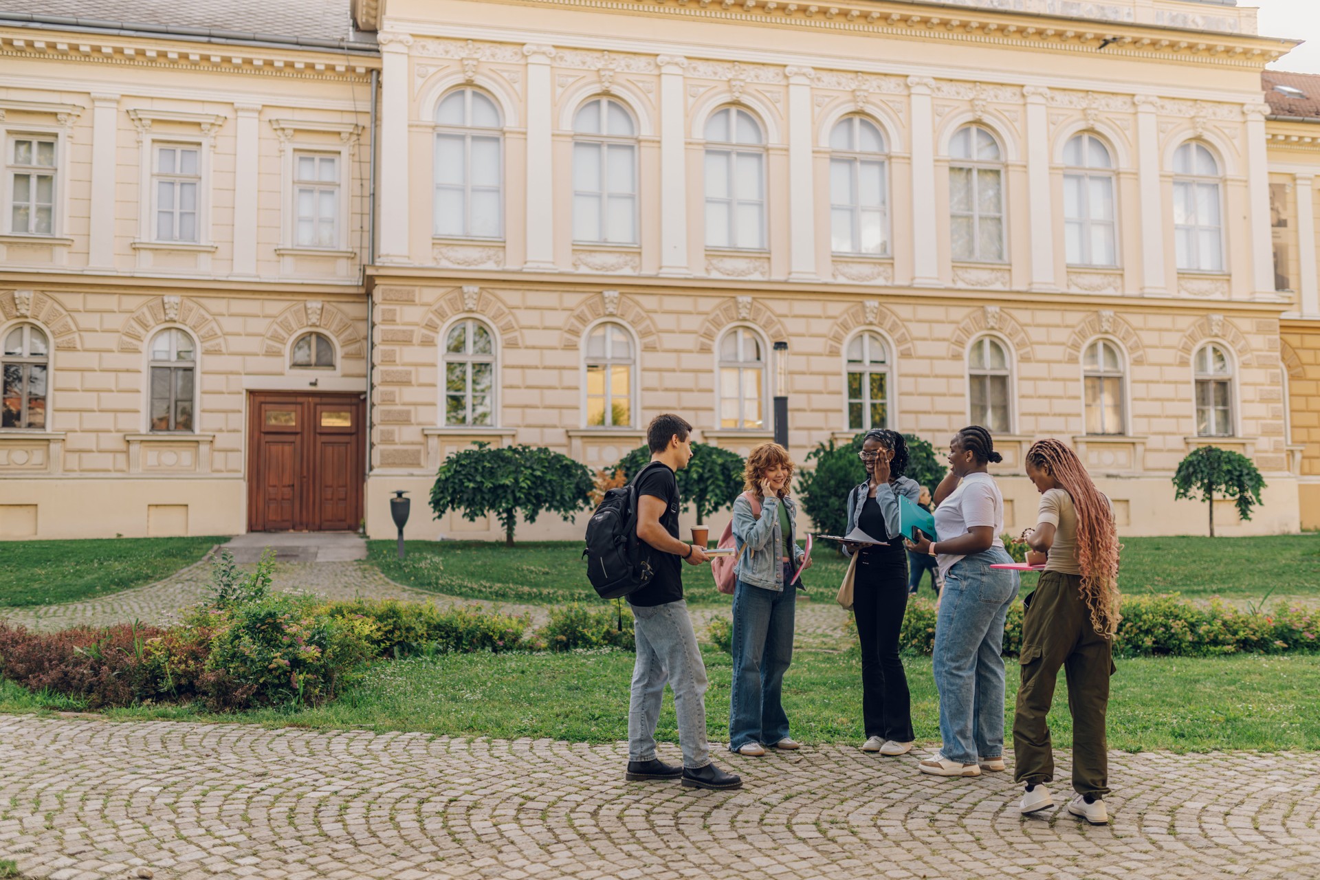 Full length shot of diverse students standing at campus with textbooks